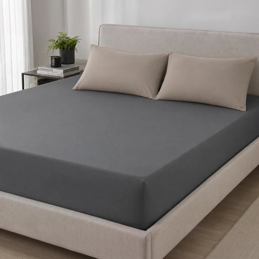 Charcoal gray 200TC 100% cotton percale fitted sheet on a bed with beige pillows, showcasing smooth fabric and a snug fit.