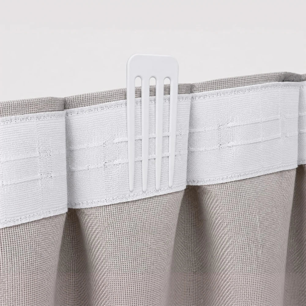 Adjustable plastic pleating hook in white mounted on a white fabric valance to create even fabric pleats.