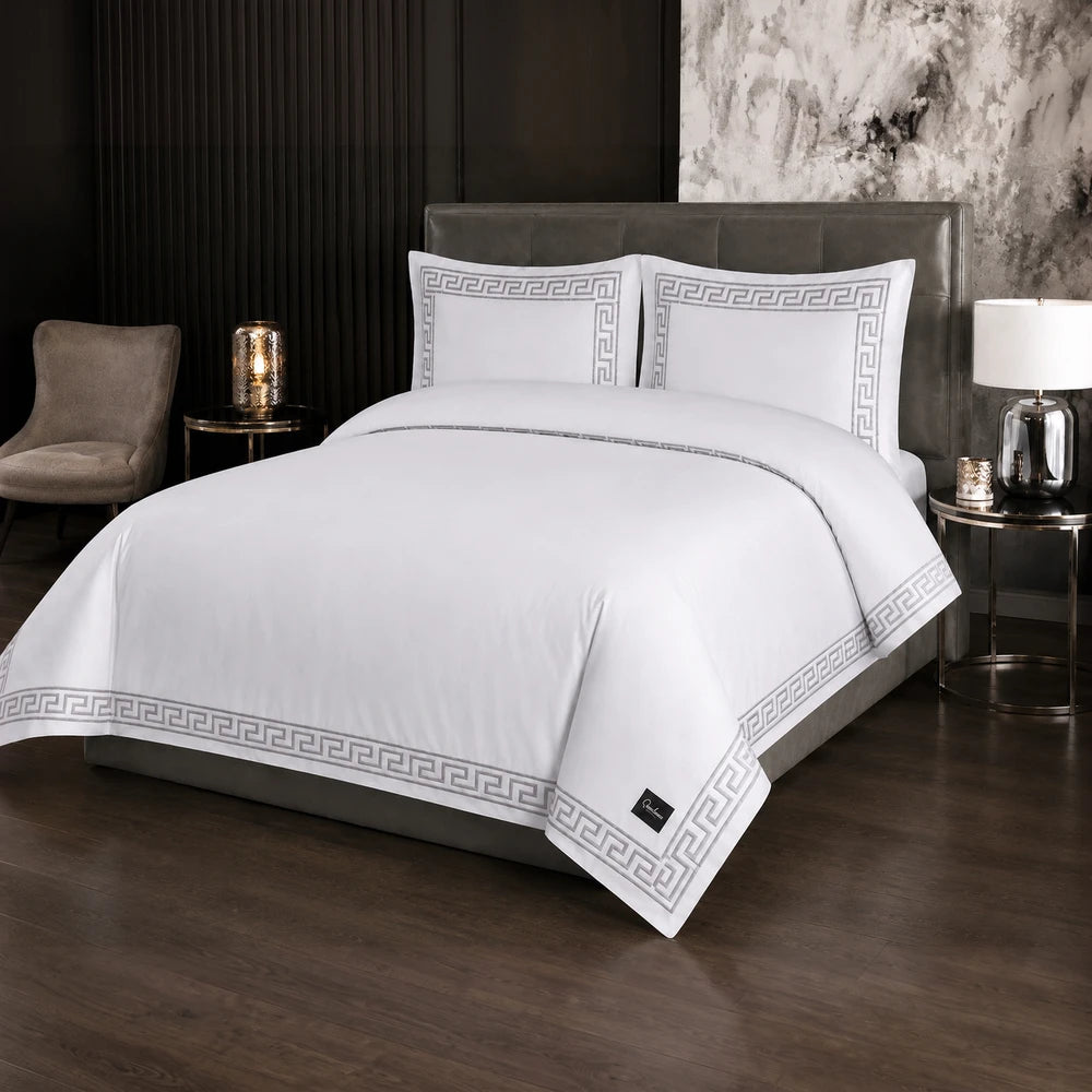 Carducci Odessa 100% cotton embroidered duvet cover in white with a gray Greek key border, shown on a bed.