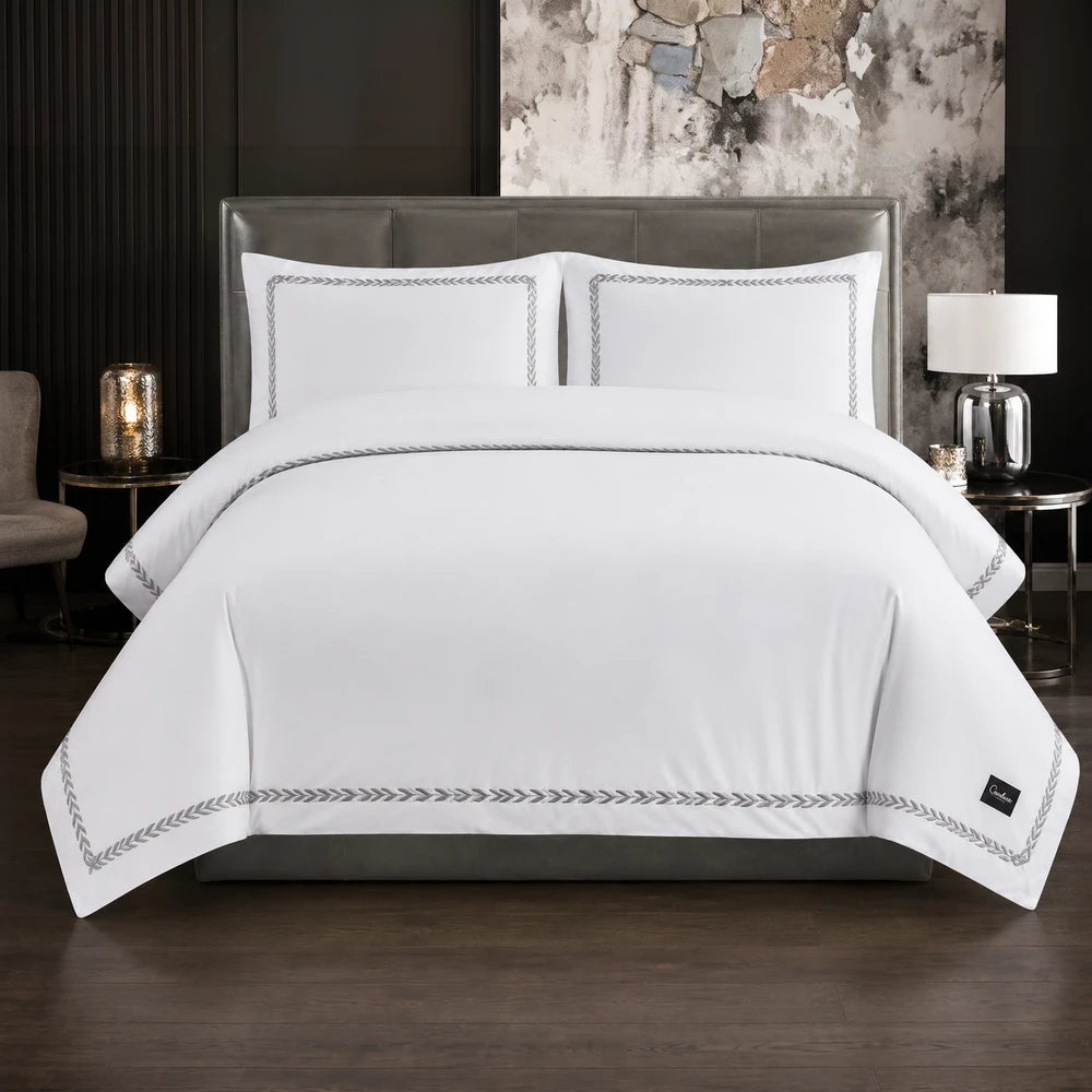 Carducci Serenity 100% cotton bedding in pure white with silver grey border embroidery, shown on a neatly made bed.