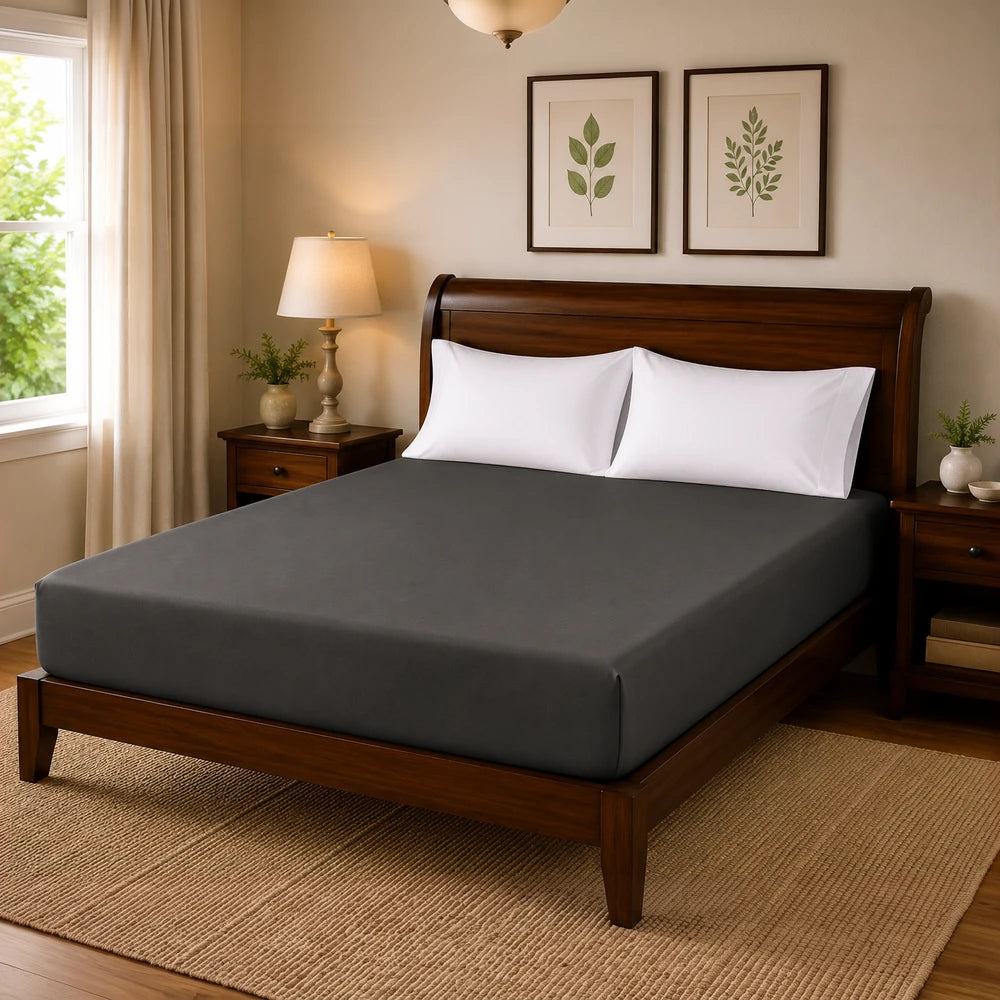 Microfibre fitted sheet in charcoal gray on a wooden bed, with white pillows, highlighting a smooth, wrinkle-free finish.