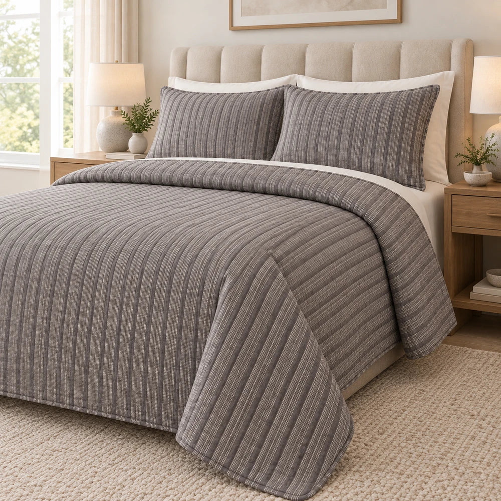 Pierre Cardin textured Pinsonic quilt set in gray with a striped pattern, shown on a bed with matching shams for a
