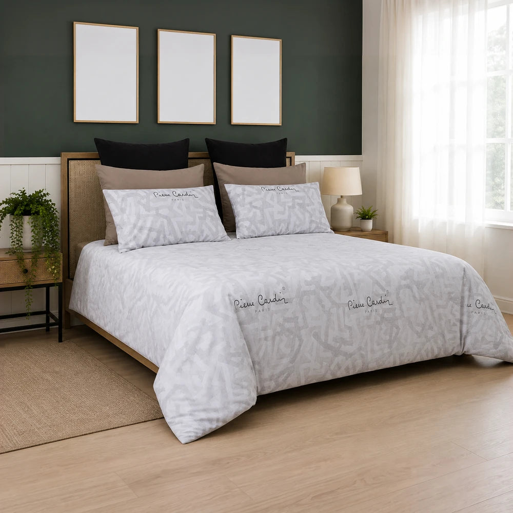 Pierre Cardin Vogue Duvet Cover Set – Jada, white with subtle gray geometric pattern, on a bed with beige and black pillows.