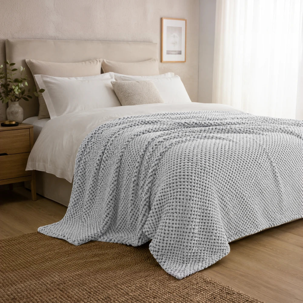 Pierre Cardin Waffle Throw in blue, soft textured knit, cozy bedroom blanket for layering on a bed