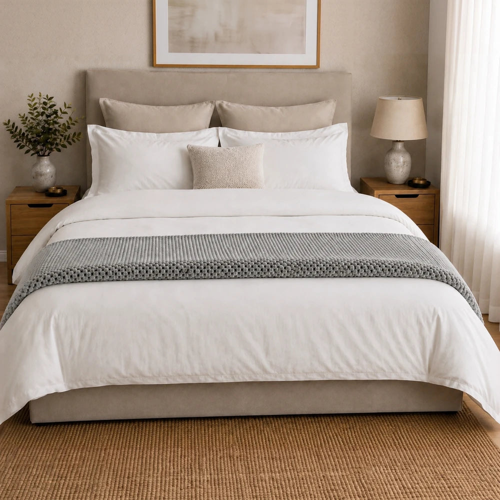 Pierre Cardin Waffle Throw in grey neatly arranged on a bed with white bedding and coordinating pillows for a cozy, premium