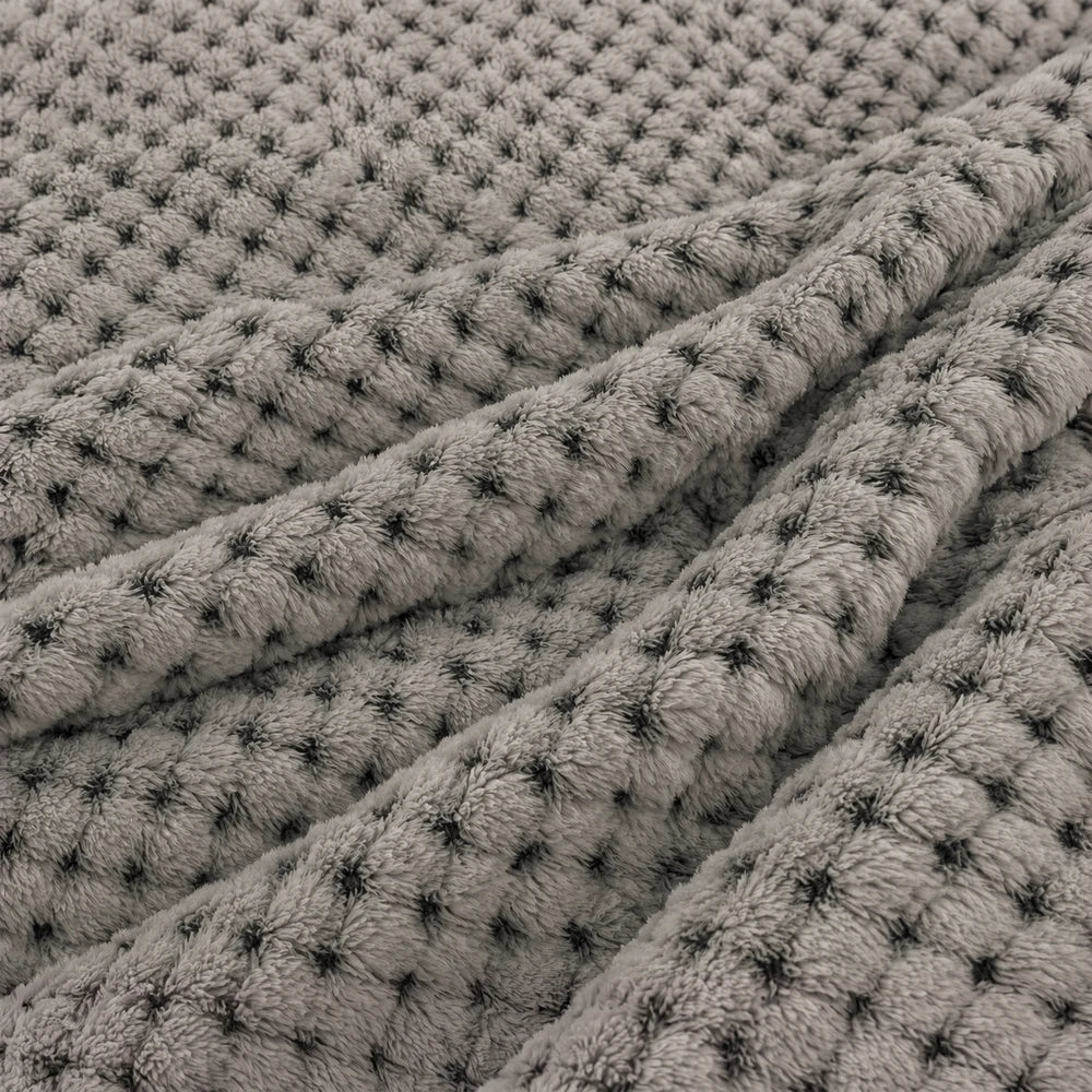 Pierre Cardin Waffle Throw in grey with plush textured waffle weave, ideal for cozy evenings and lounging on the sofa.