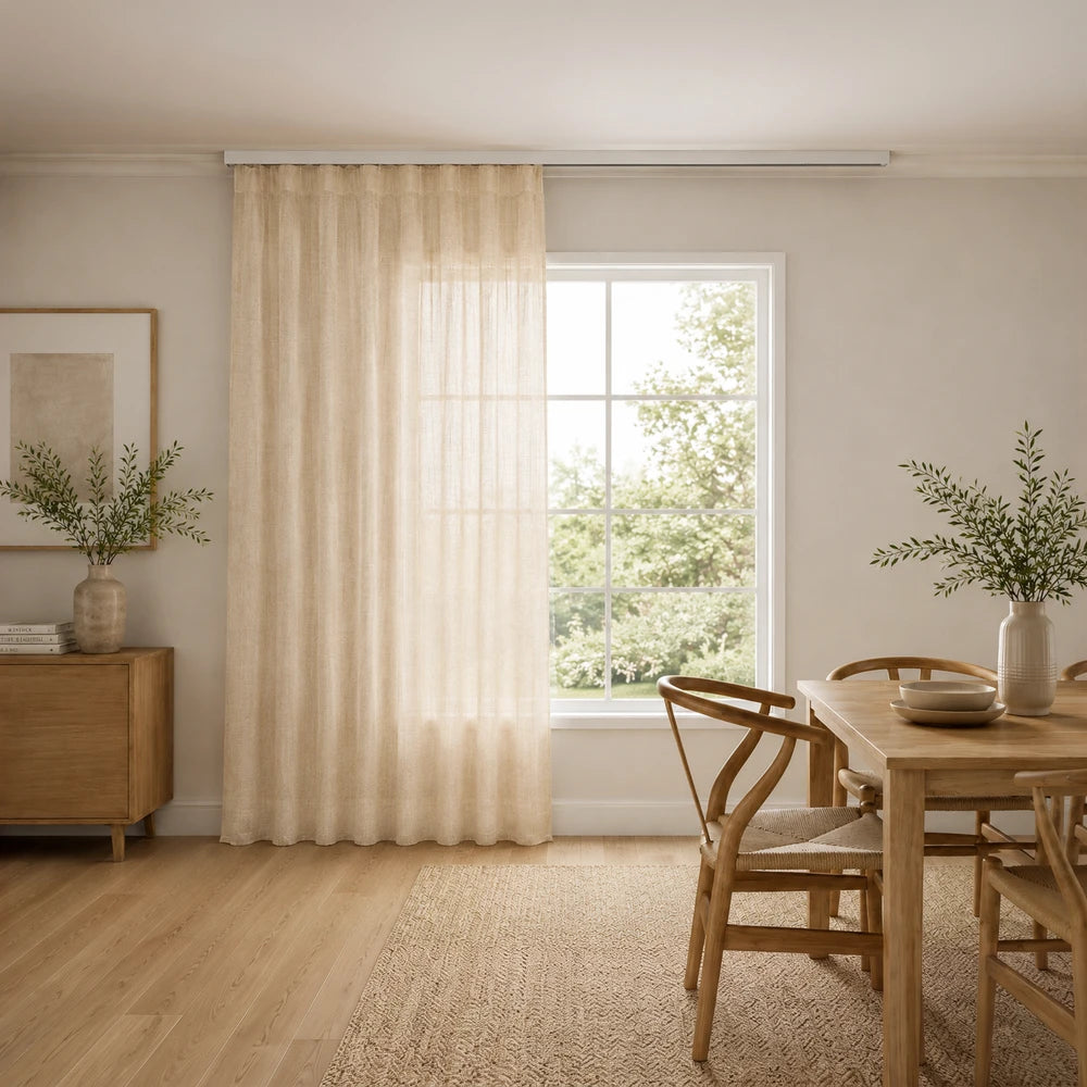 Premium taped muslin ready-to-hang curtain in beige, soft light-filtering fabric, shown draped beside a window in a cozy