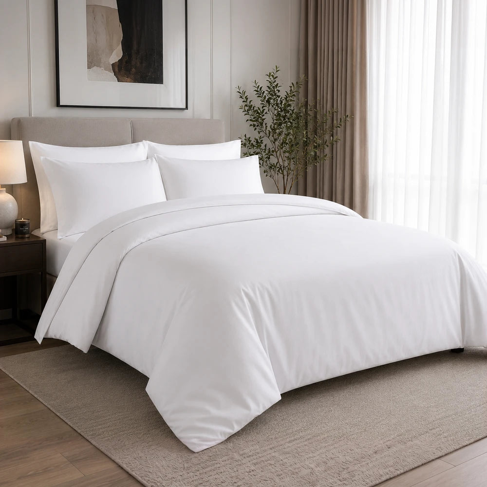 White 200TC 100% cotton percale plain duvet cover set with matching pillowcases on a neatly made bed