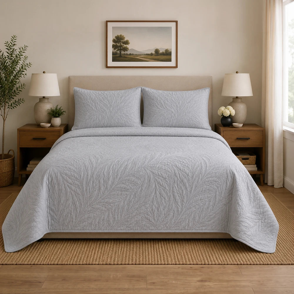 Carducci Katarina 100% cotton quilt in light gray on a neatly made bed with matching gray pillow shams.