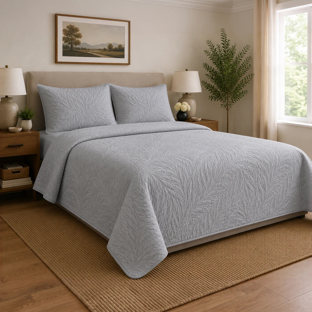 Carducci Katarina 100% cotton quilt in light gray with leaf quilting, on a neatly made bed.