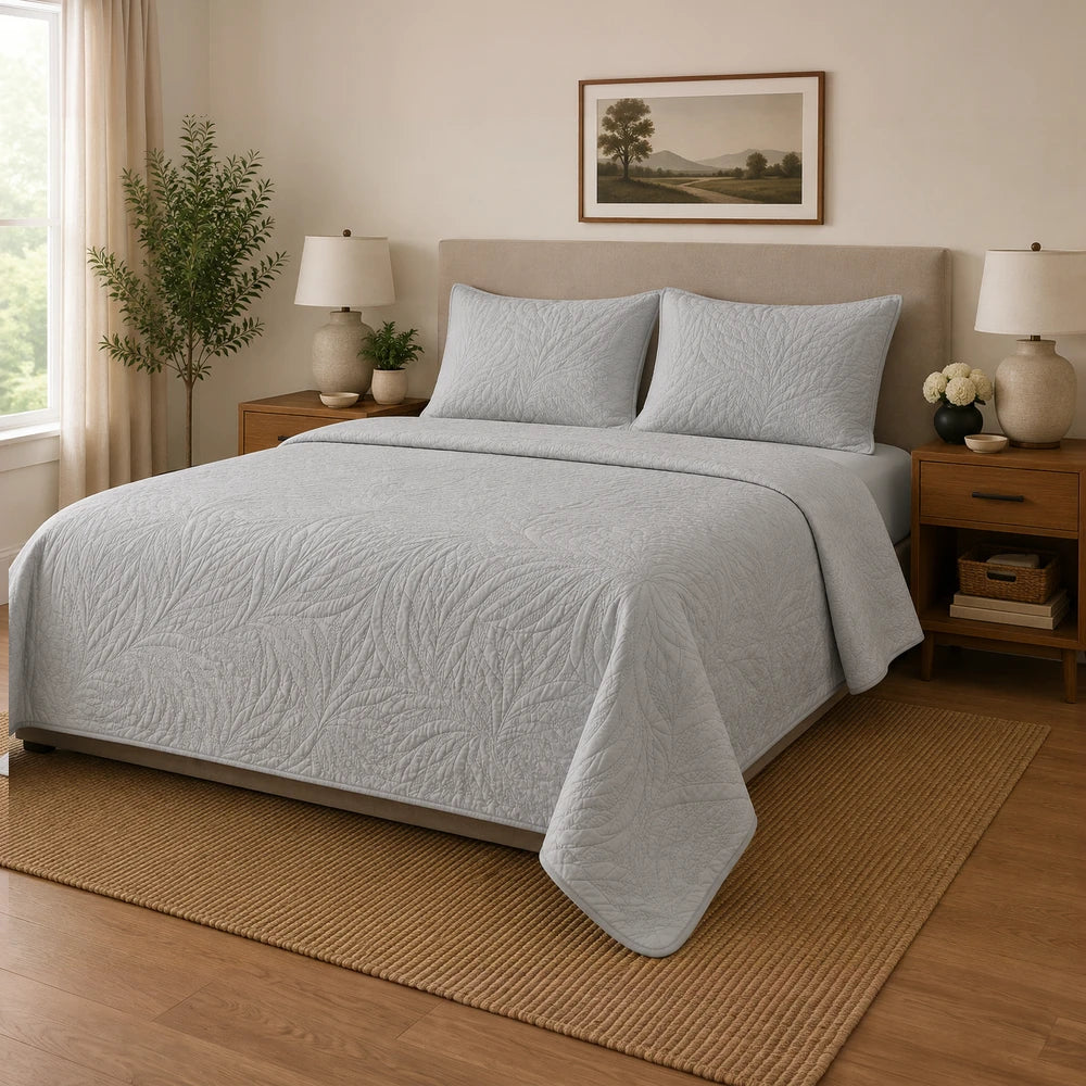 Carducci Katarina 100% cotton quilt in light gray on a neatly made bed with matching pillow shams.