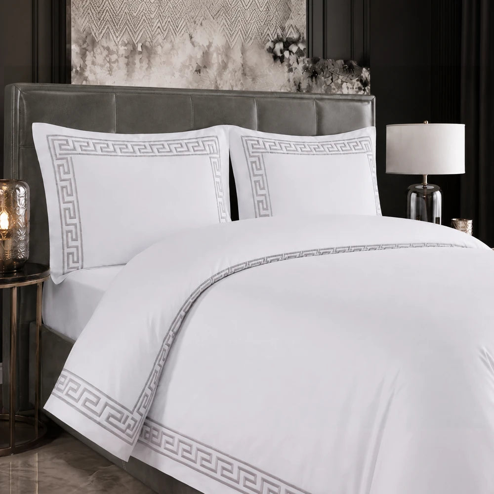 Carducci Odessa 100% cotton embroidered duvet cover in white with grey geometric border, shown on a neatly made bed.