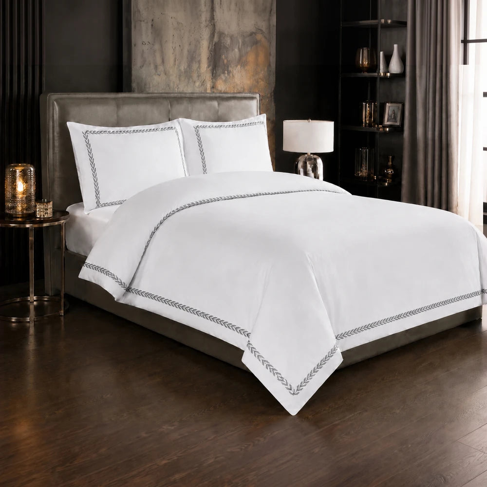 Carducci Serenity 100% cotton bedding in pure white with silver grey embroidered border, showcased on a neatly made bed.