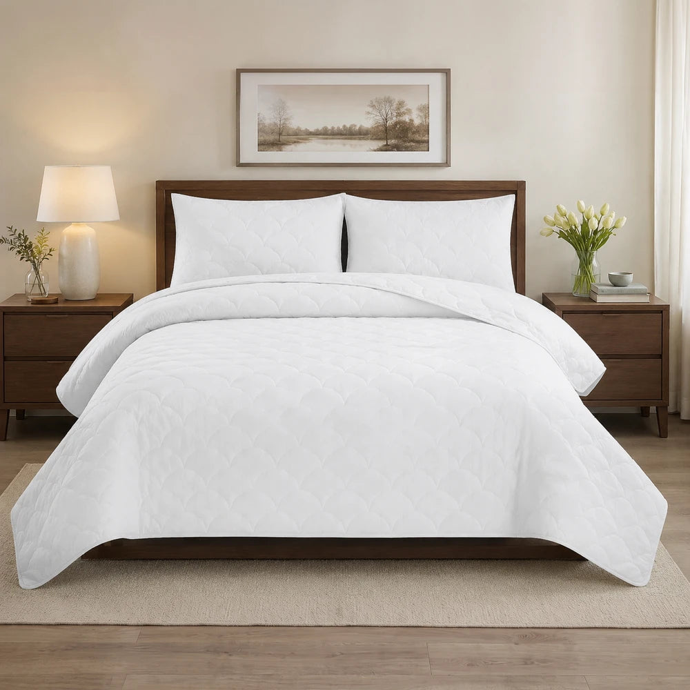 Carducci Washer Quilt Set in white with a quilted cloud-like pattern on a wooden bed.