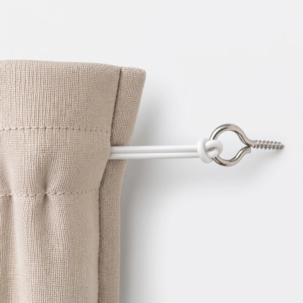 Close-up of a curtain wire securing a beige linen curtain to a wall with a metal eye hook and white flexible wires.