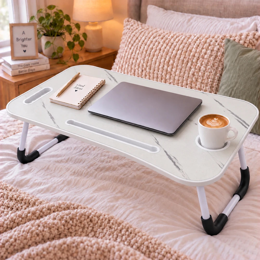 Multi-Functional Foldable Laptop Table with marble-like top and white legs, shown on a bed with laptop and coffee mug.