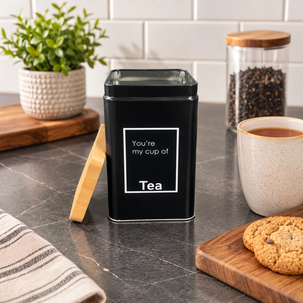 Matte black bamboo kitchen storage tin with the word Tea on the front label and a removable lid.