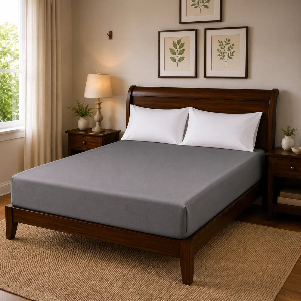 Microfibre fitted sheet in gray on a wooden bed with white pillows, highlighting a smooth finish and wrinkle resistance.