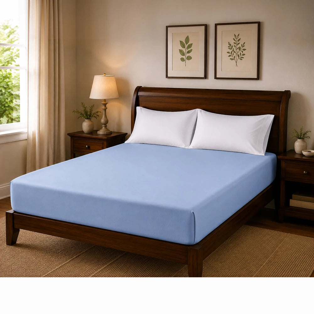 Microfibre fitted sheet in light blue on a wooden bed with white pillows, soft, breathable fabric.