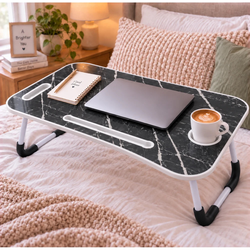 Multi-Functional Foldable Laptop Table & Serving Tray with black marble top and white frame, used beside a laptop on a bed.