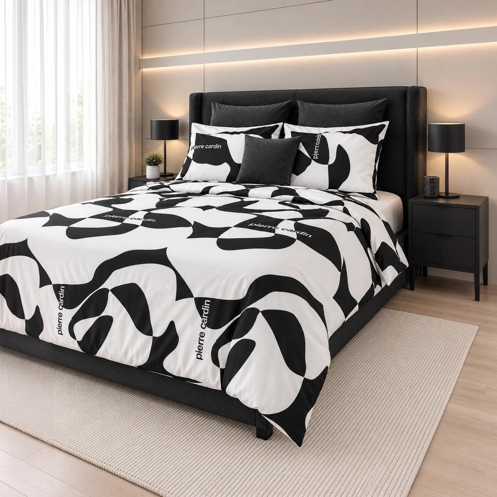 Pierre Cardin duvet cover set in black and white abstract pattern on a dark upholstered bed with matching pillow shams.