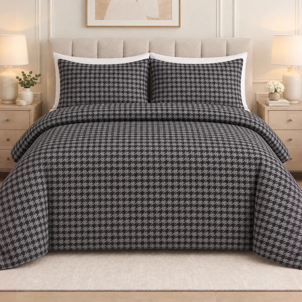 3pc Pierre Cardin printed houndstooth quilt set on a bed in gray and black with matching pillow shams and white borders.