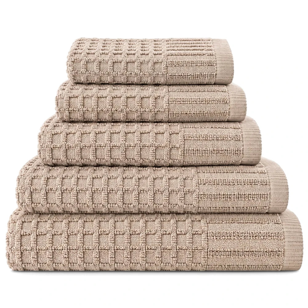 Five neatly folded premium 100% cotton waffle weave bath towels in a beige color, stacked on a plain white background.